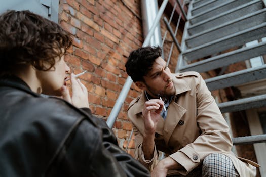 Young adults taking a smoking break on metal stairs, embodying a modern urban lifestyle.