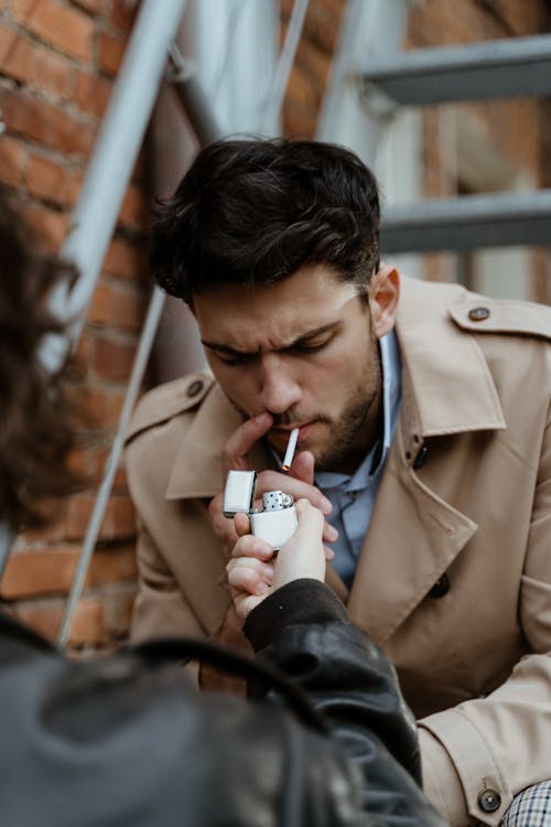 Free Photo of a Man in a Beige Coat Lighting a Cigarette Stock Photo