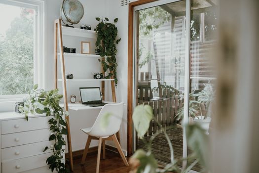 Minimalist home office with Scandinavian design, featuring greenery and natural light.