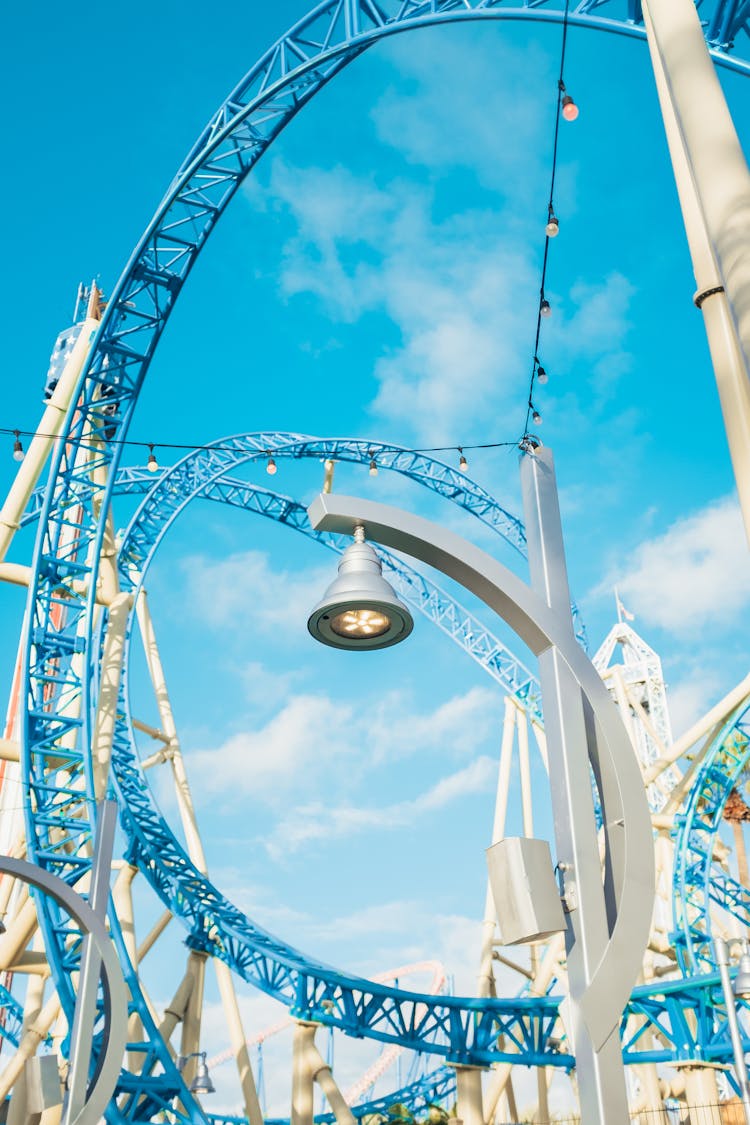 A Blue Metal Roller Coaster Ramp With Loops Under Blue Sky