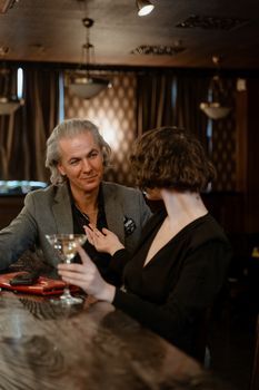 Mature couple enjoying a sophisticated night out with drinks in a stylish bar.