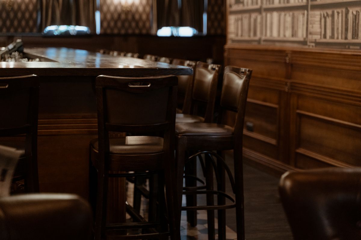 Interior de pub cu bar de lemn inchis si taburete de piele