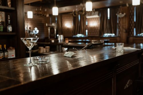 Free A cozy bar counter with cocktail glasses and dim lighting, inviting ambiance. Stock Photo