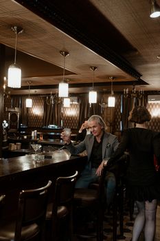 Classic lounge bar setting with elegant patrons enjoying drinks under warm lighting.