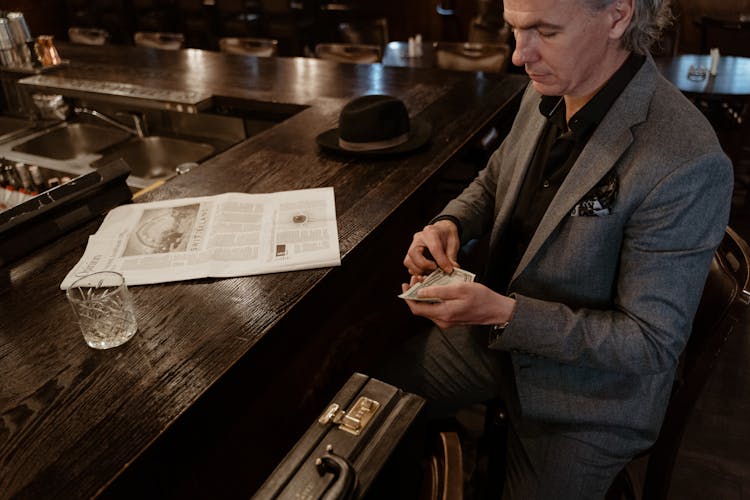 A Man In Gray Suit Jacket Holding Money