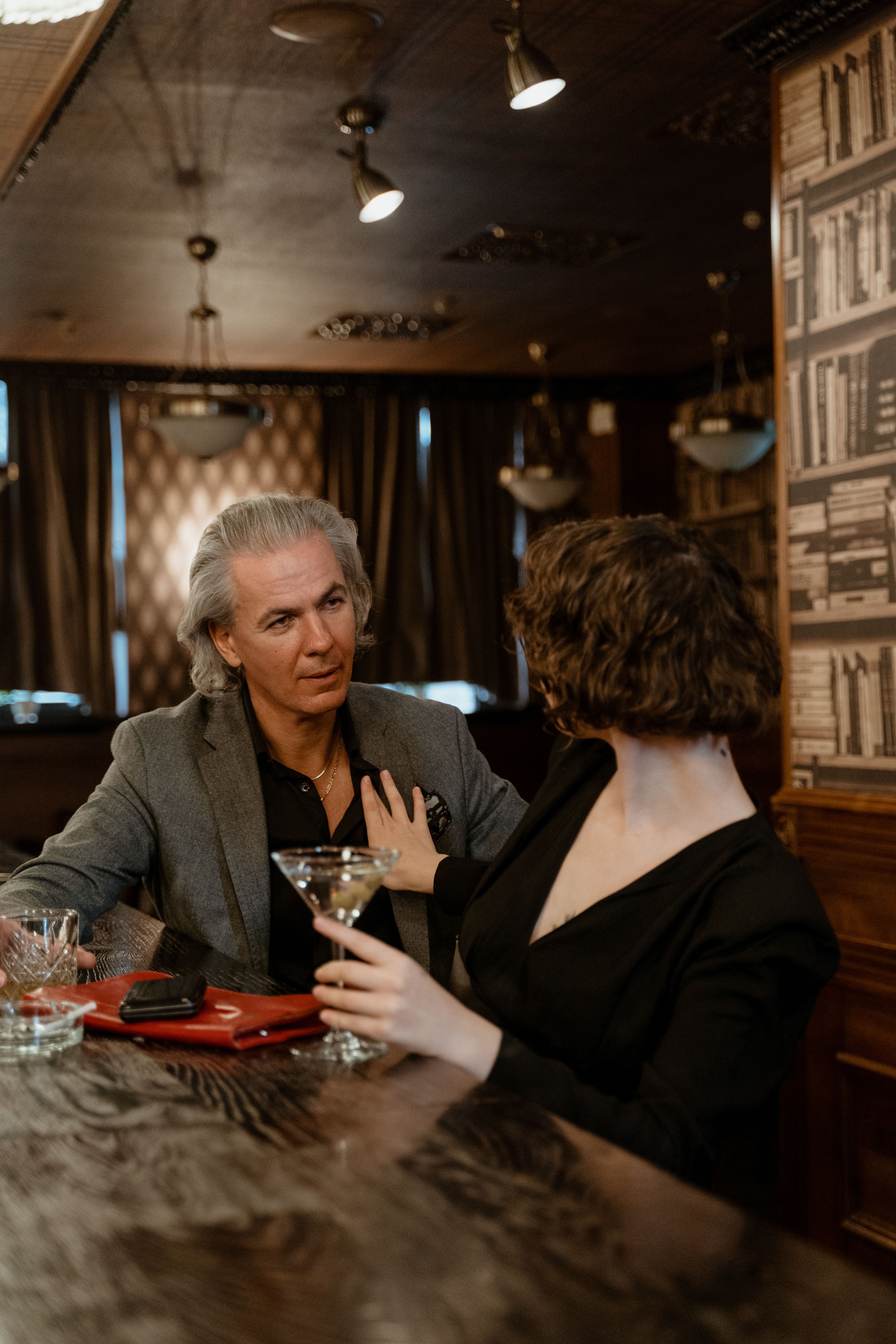 A mature couple engaging in conversation and drinks at a cozy bar setting.