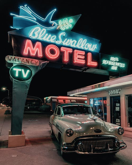 Photograph of a Vintage Car Under Neon Signages