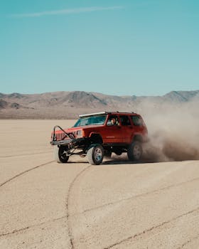 A rugged SUV powers through the sandy desert, creating a dynamic dust cloud.