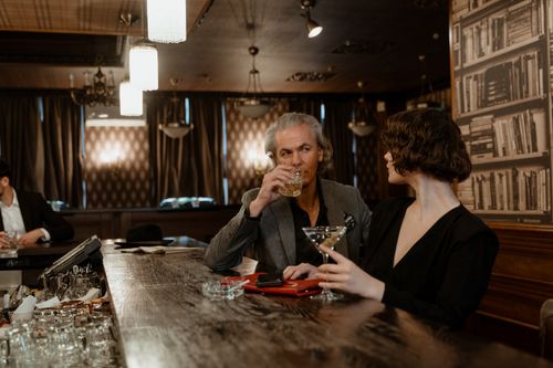 Free An elegant couple enjoying drinks in an intimate and stylish bar setting. Stock Photo