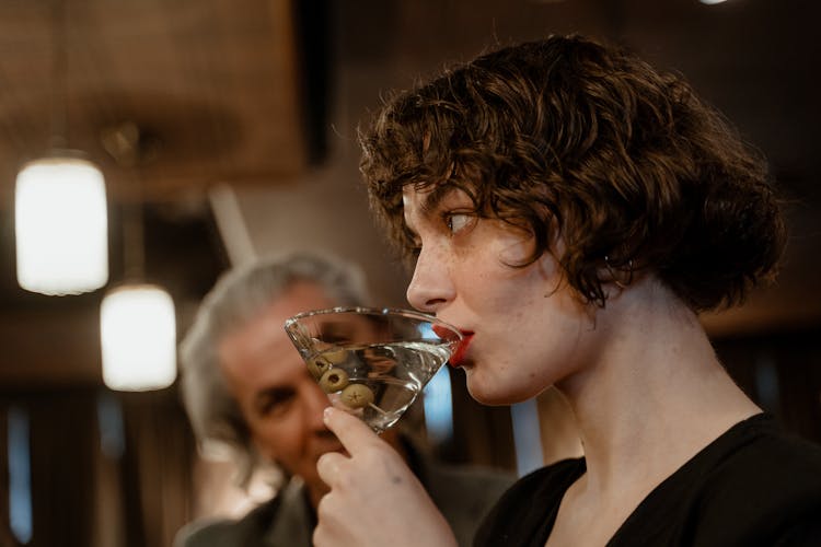 A Woman Sipping Martini With Green Olives