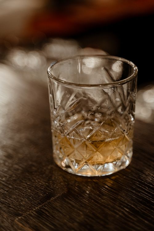 Free A close-up shot of whiskey served in a patterned crystal glass on a wooden surface. Stock Photo