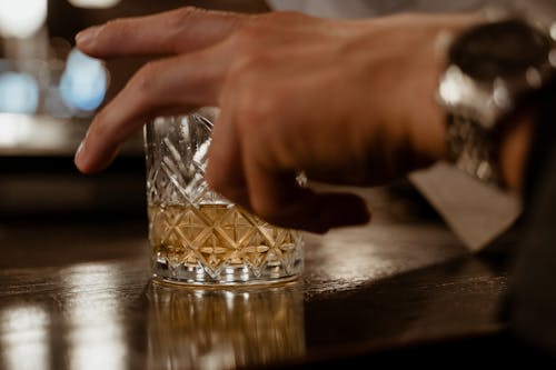 A Person Grabbing a Glass of Whiskey