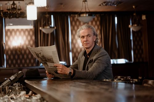 Free Mature man in a stylish suit reads a newspaper at an elegant bar, exuding sophistication and class. Stock Photo