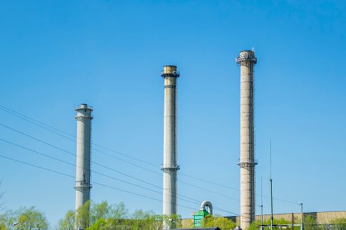 Free Three tall industrial chimneys with a clear blue sky background. Stock Photo