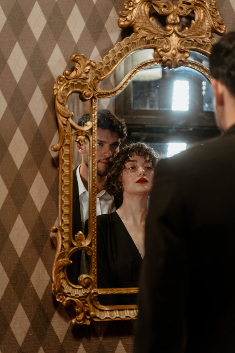 A Couple Standing In Front Of A Mirror