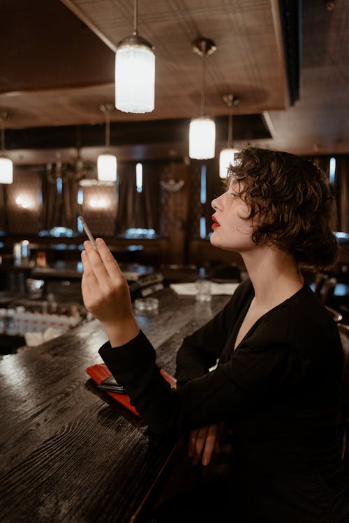 A Woman Sitting at the Bar Counter Smoking a Cigarette