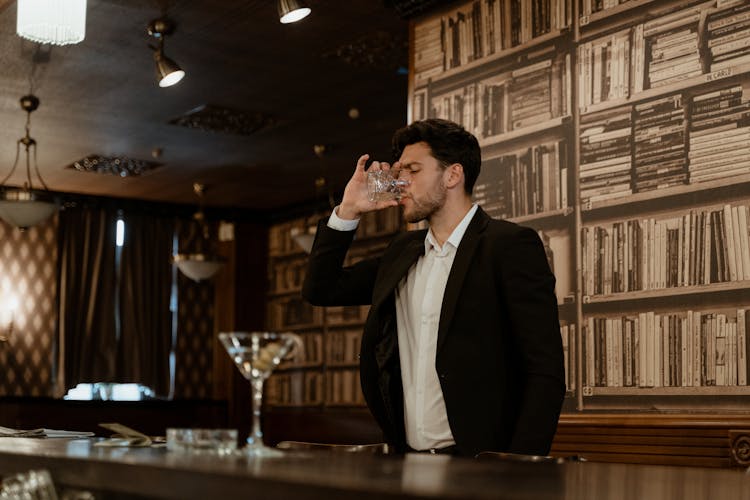 A Man In Black Suit Jacket Drinking A Wine