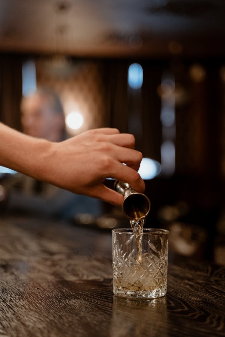 Close-Up Shot Of A Person Pouring Liquor In A Glass