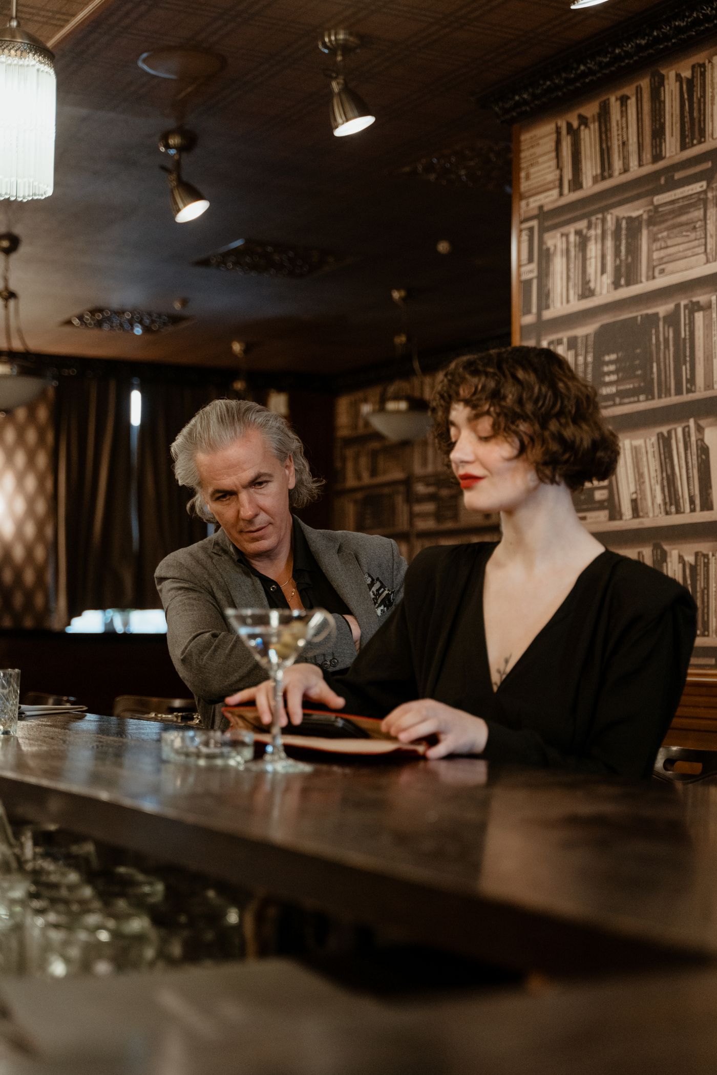 Elegant adult woman and mature gentleman enjoying drinks in a premium bar