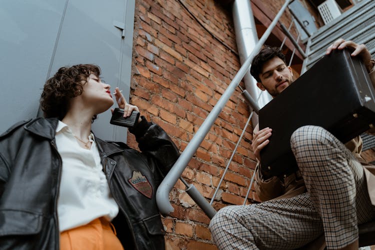 A Woman Smoking Beside A Man With A Briefcase