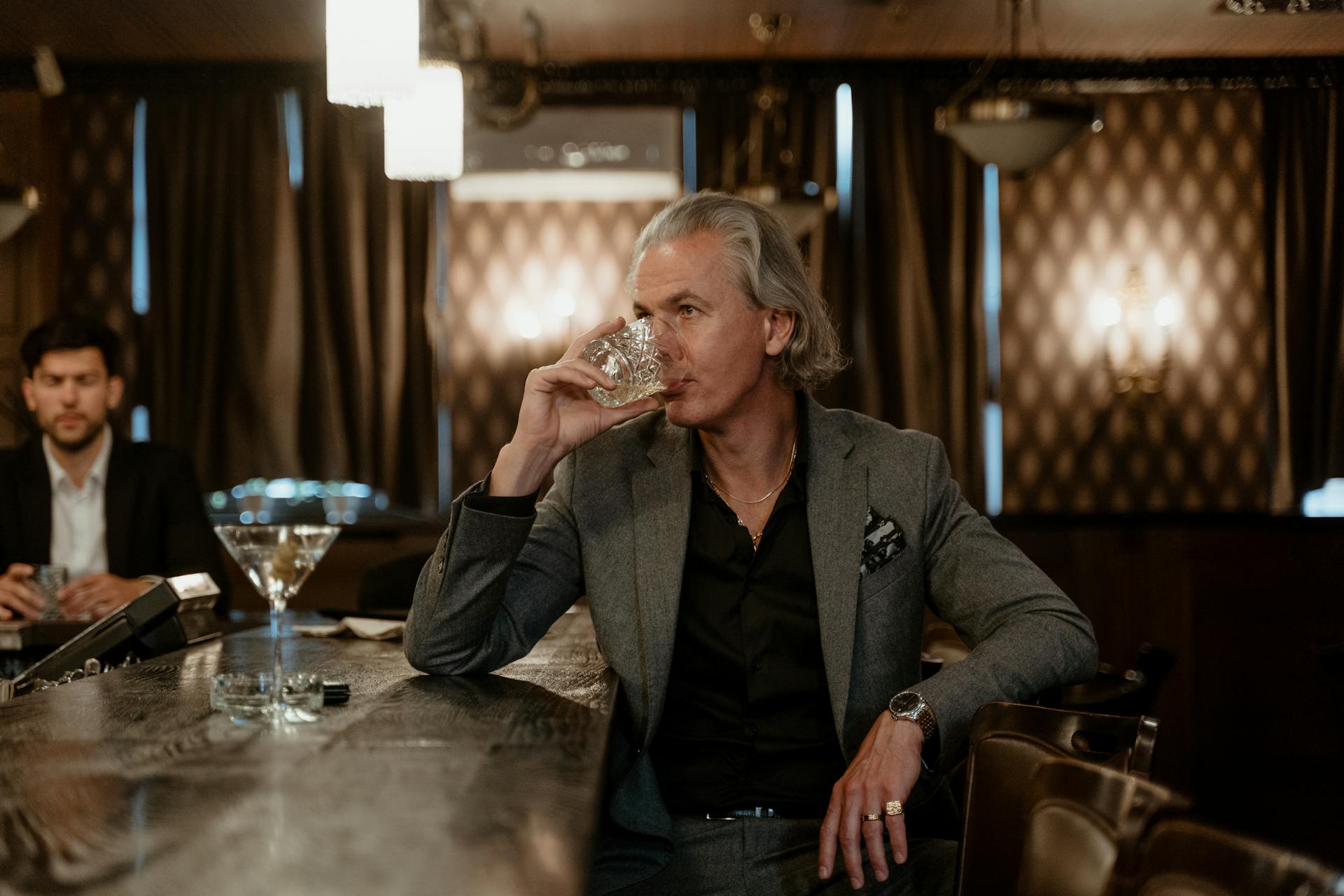 Man in Gray Suit Jacket Drinking a Glass of Liquor