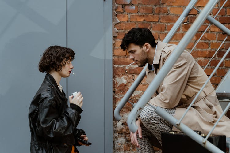 Man And Woman Smoking Cigarettes Together
