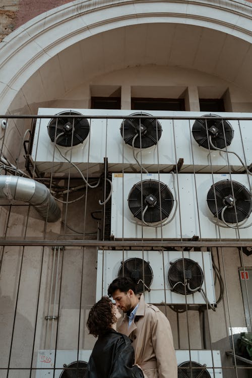 Man and Woman Kissing near the Aircon Blowers