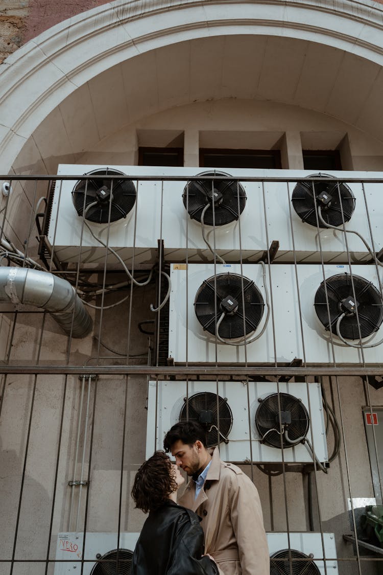 Man And Woman Kissing Near The Aircon Blowers