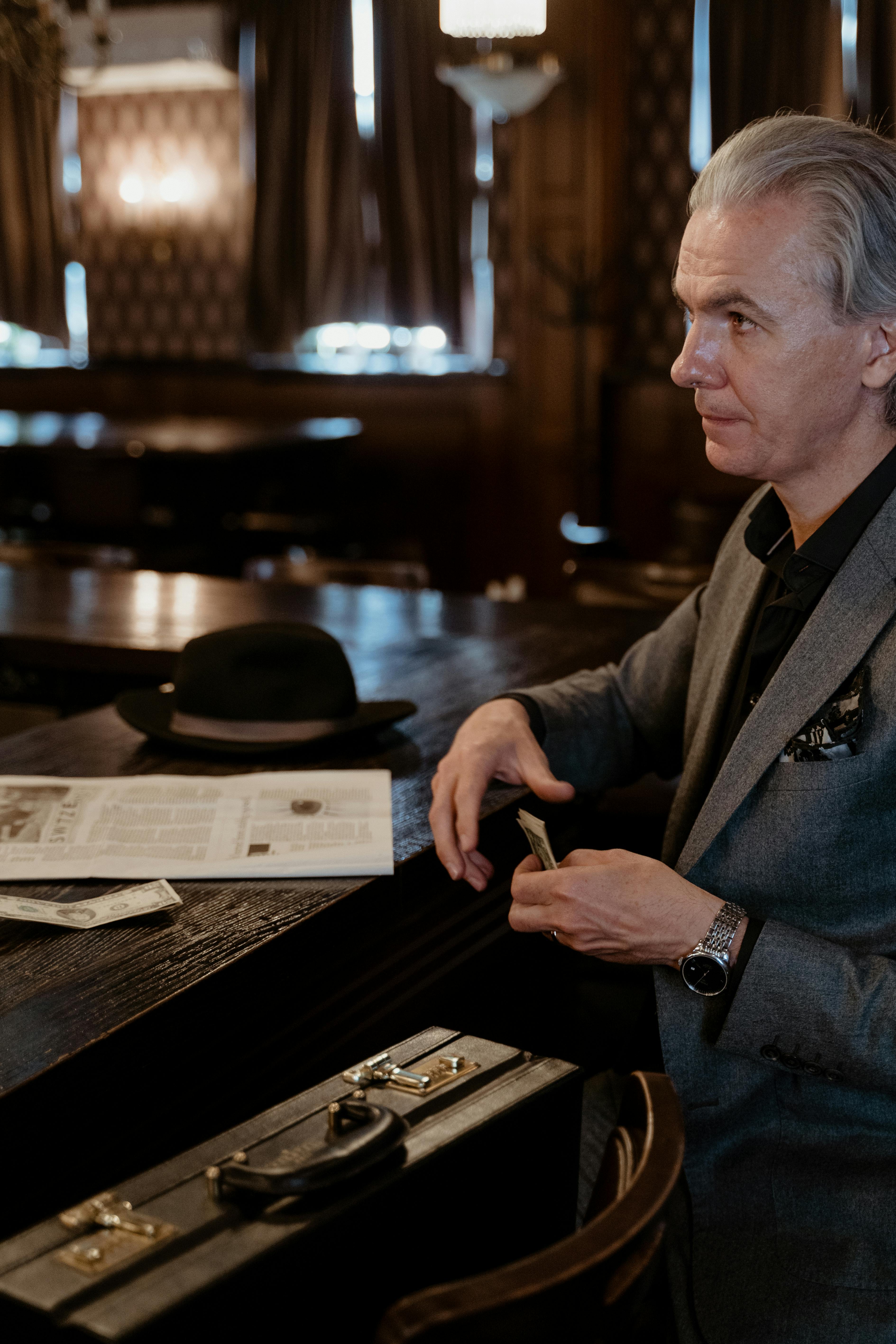 man in black suit jacket holding his money