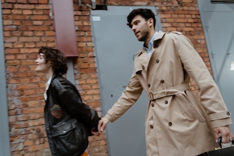 Man In Beige Trench Coat Carrying A Black Suitcase 