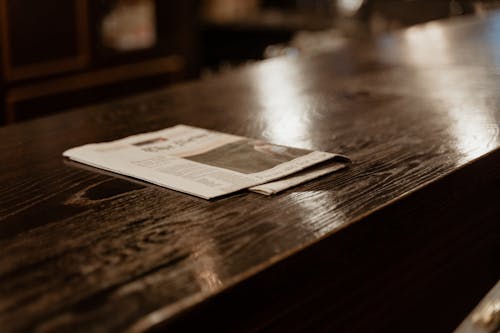 Newspaper on Brown Wooden Table