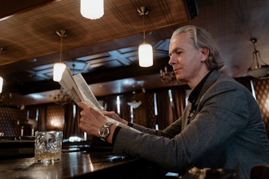 Sophisticated man in a vintage bar reads a newspaper, evoking a classic and retro atmosphere.