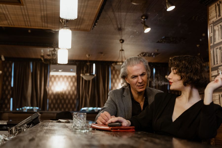 Adult woman and mature gentleman having a respectful conversation in an elegant bar