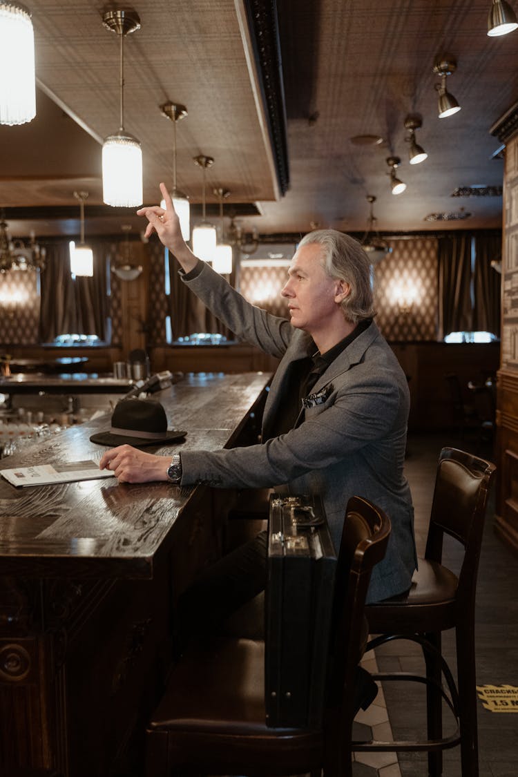 A Man In Gray Suit Sitting At The Bar