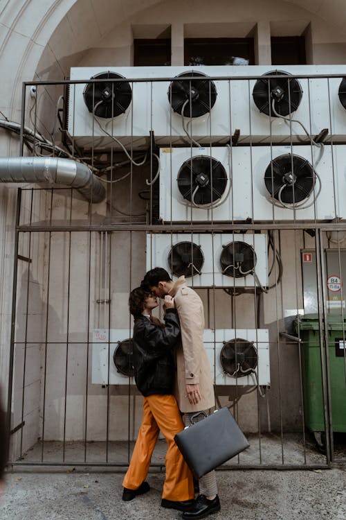 Woman in Leather Jacket and Man in Brown Jacket Kissing 