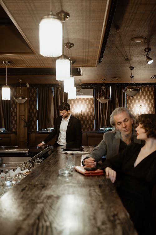 A Man and a Woman Sitting on the Bar Counter Chairs