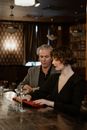 Woman in Black V Neck Shirt Sitting Beside Man in Gray Blazer
