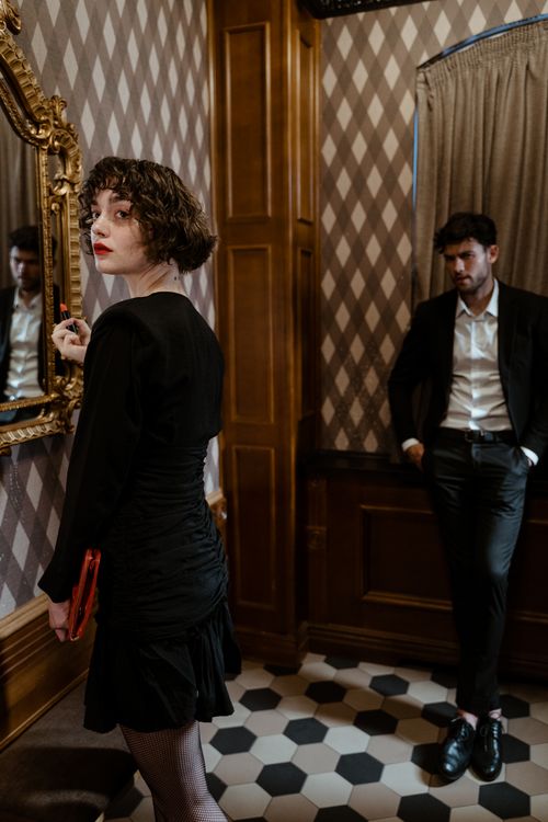 Free Couple in formal attire in a vintage room with wooden interiors and a decorative mirror. Stock Photo