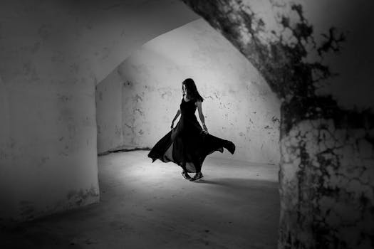 A woman elegantly twirls in a mysterious, dimly lit room. Captivating shadows enhance the eerie ambiance.
