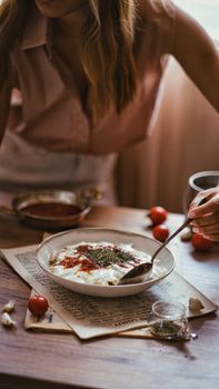 Appetizing bowl of yogurt with herbs and spices on a wooden table.