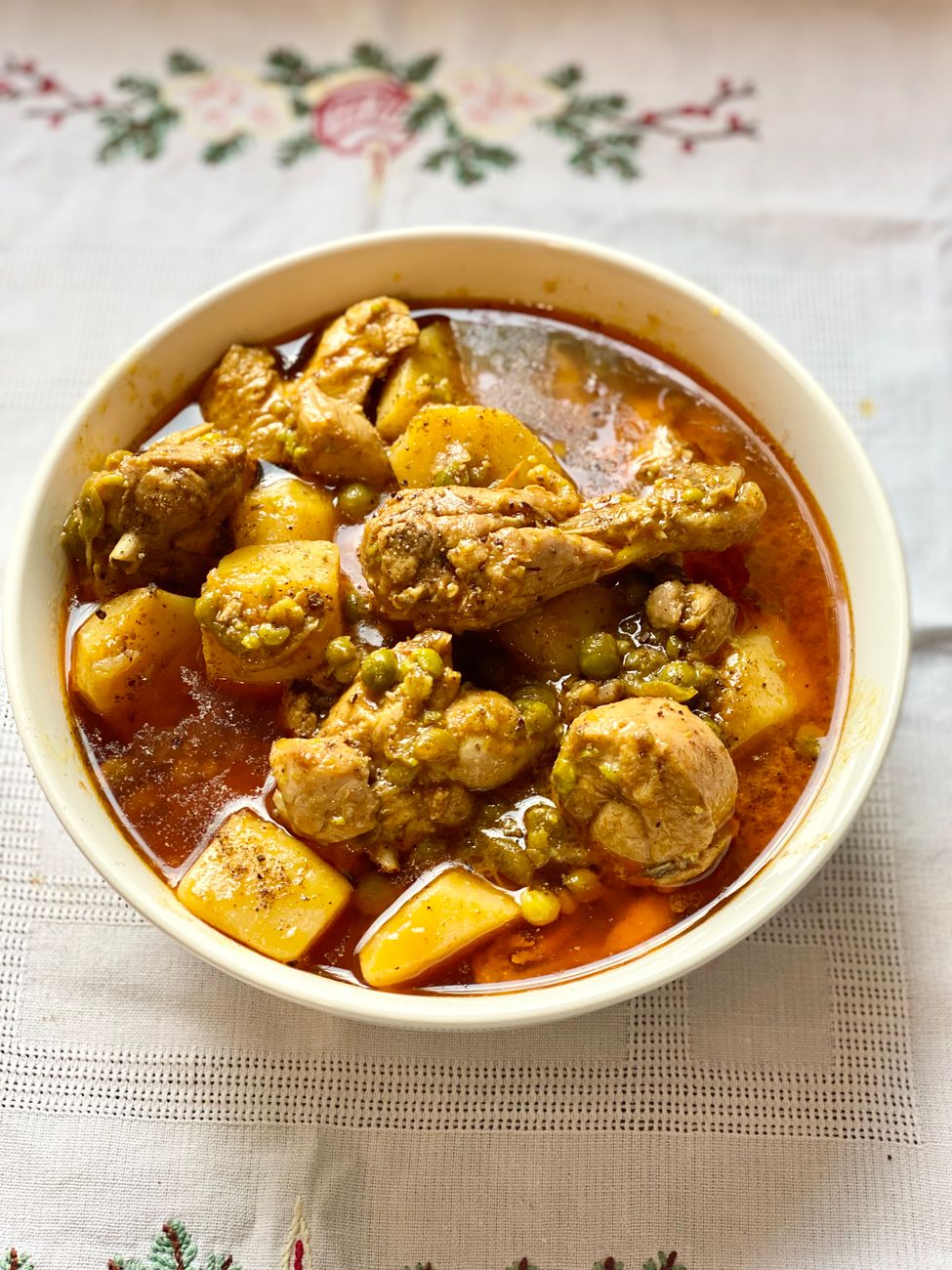 A bowl of Caribbean curry stew with tender chicken pieces, carrots, potatoes, and parsnip in a creamy coconut broth, garnished with a lime wedge
