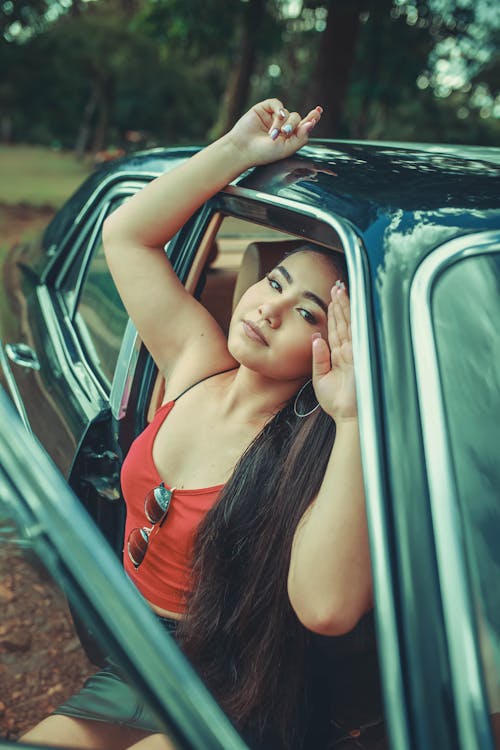 Woman in Red Tank Top Leaning on Black Car