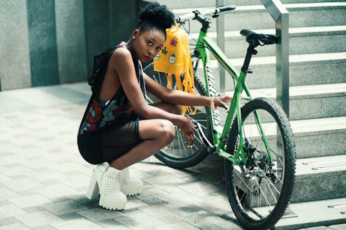 Frau, Die Schwarzes Kleid Sitzt, Das Nahe Grünem Fahrrad Sitzt