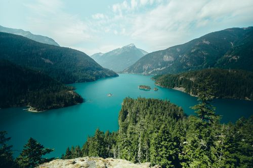 Free Breathtaking view of a mountain lake surrounded by lush forests and peaks. Stock Photo