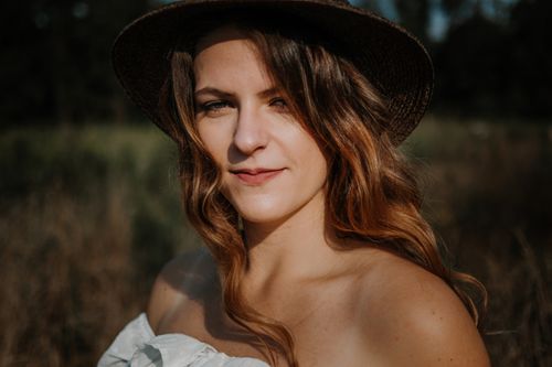 Free A captivating outdoor portrait of a woman wearing a sun hat, featuring a warm and natural ambiance. Stock Photo