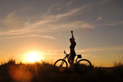 Silhouette of Woman Riding Bicycle during Sunset