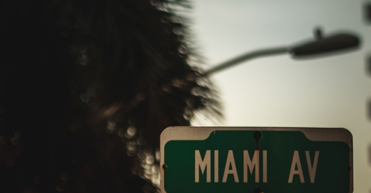 A moody street sign for Miami Avenue captured at twilight with blurred city elements.