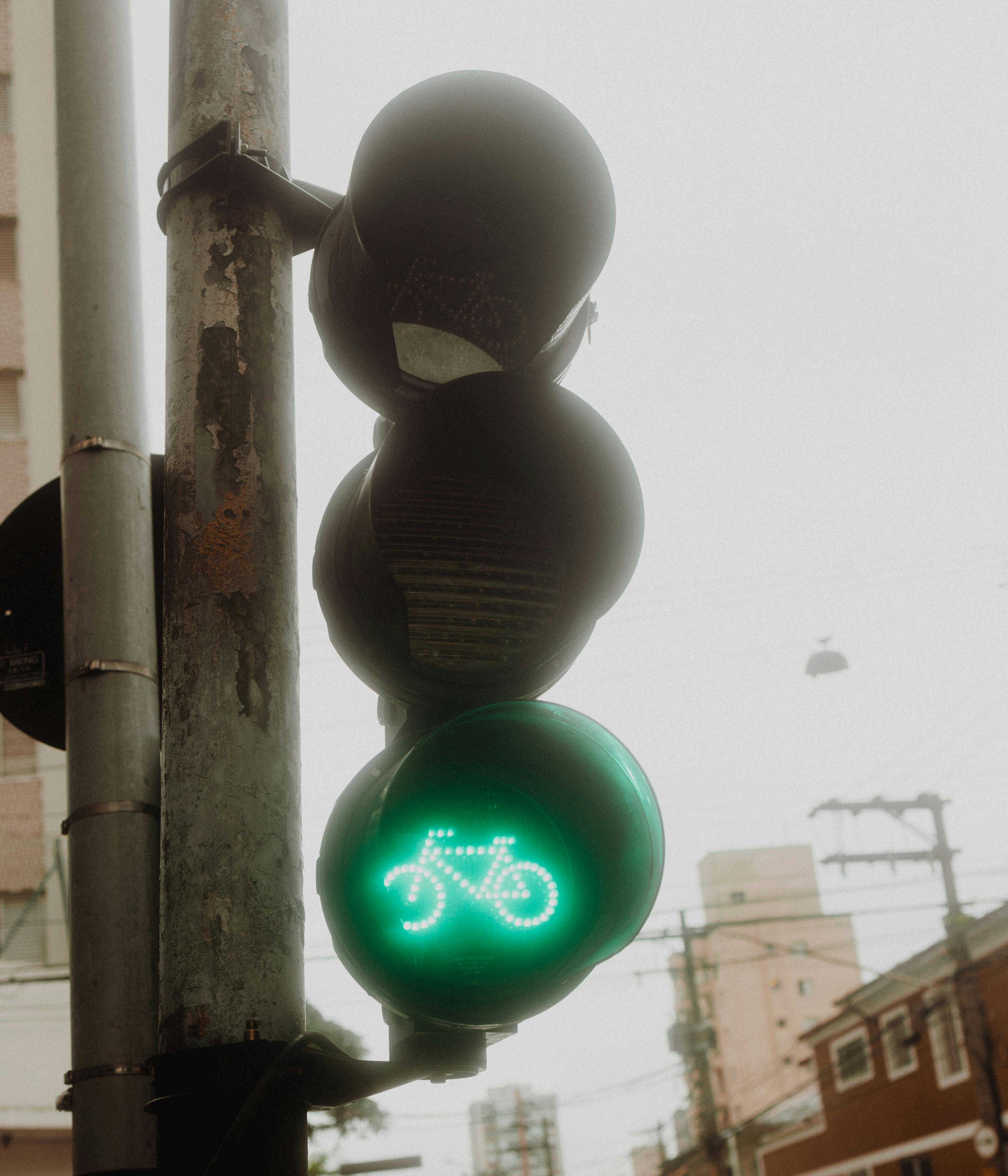 Close-up of a green bicycle traffic light indicating go signal on a cloudy day in the city.