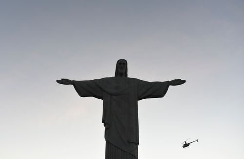 Free Silhouette of Christ the Redeemer statue with a helicopter in the sky during dusk. Stock Photo