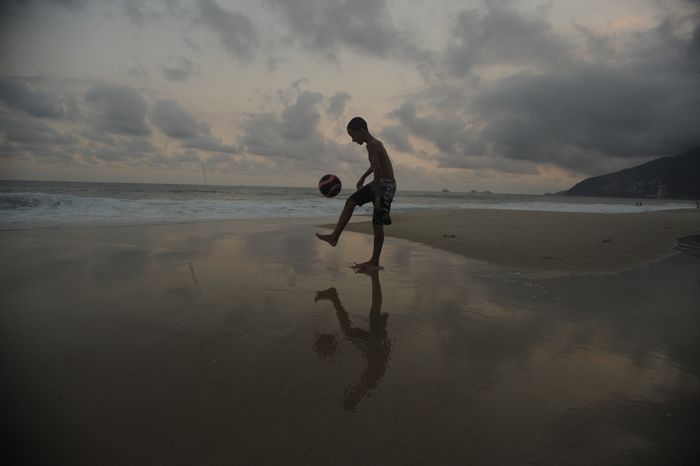 Pontapé na bola na praia ao pôr-do-sol